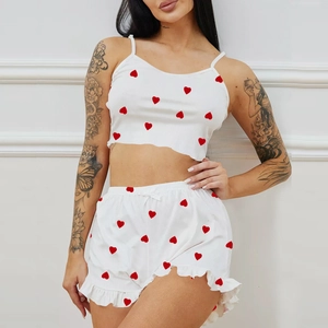Detail of white pajamas with red hearts featuring ribbed texture and ruffled hemline