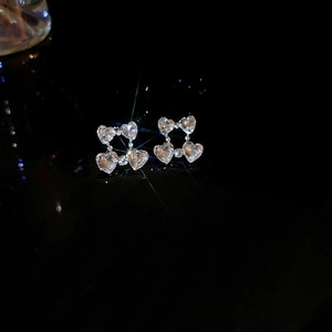 Close-up of heart-shaped crystal stud earrings with a brilliant starburst sparkle effect