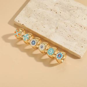 Detailed macro view of 14K gold plated rings with colorful enamel evil eye flower patterns