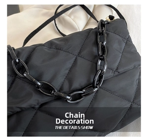 Detail of the black quilted puffer bag featuring a bold chunky chain decoration