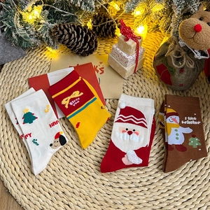 Flat lay of four pairs of festive Christmas themed cotton socks on a straw mat background
