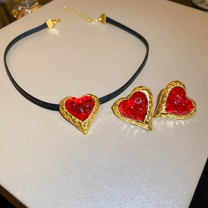 Macro detail of red heart jewelry set with vintage hammered gold edges and choker cord