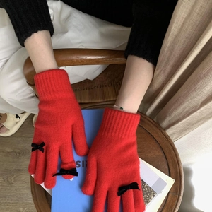 Detail of red knitted gloves with small black bow accents in a cozy winter setting