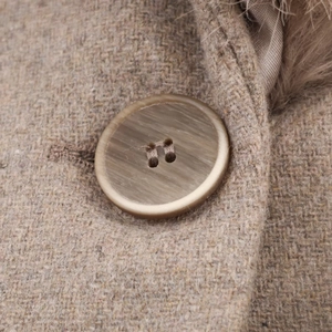 Dettaglio macro del tessuto in lana kaki e bottone stile corno su un cappotto in ecopelliccia