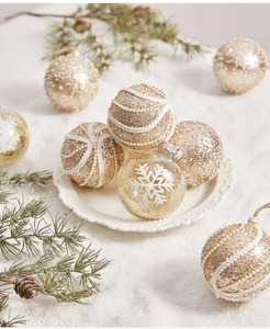 Close-up of champagne gold glitter Christmas balls with pearl accents and pine cones