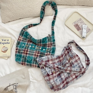 Détail de sacs bandoulière en toile à carreaux avec boutons et étiquette de marque latérale