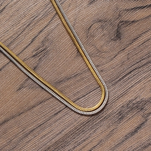 Detail of 2mm round snake chain necklaces in gold and silver finishes on wood background