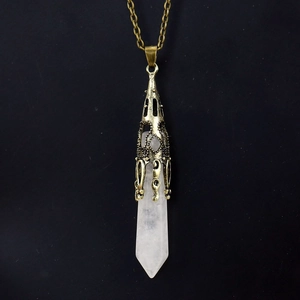 Detailed view of white crystal hexagonal point pendant with bronze filigree cap