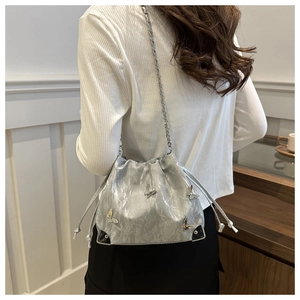 Detail of silver drawstring bucket bag featuring metallic butterfly studs and chain strap
