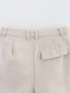 Detail view of beige linen-textured shorts featuring a waist belt loop and a flap pocket