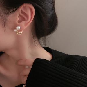 Close-up of elegant C-shaped golden earrings with pearls worn on model's ear
