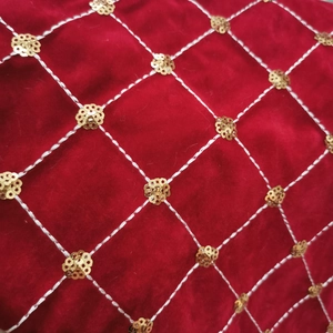 Detail of red velvet fabric with white quilted stitching and gold sequin accents