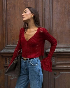 Detail of red hollow knit cardigan with V-neck, flared sleeves and intricate crochet texture