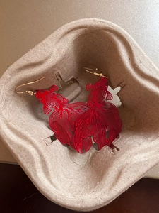 Detail of red hollow metal koi fish earrings in a molded pulp packaging tray
