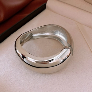 Close-up of wide irregular silver bangle with polished finish and hinge detail