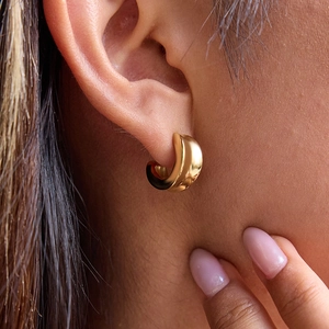 Macro shot of 18K gold plated concave hoop earrings on a model showing polished finish