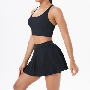 Detail view of black cross-back sports bra and pleated tennis skirt set on model