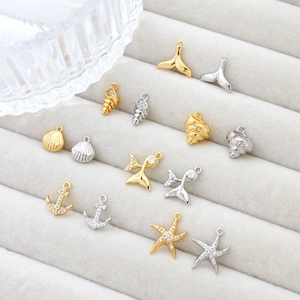 Various 14k gold plated marine charms with zircon on beige velvet jewelry display