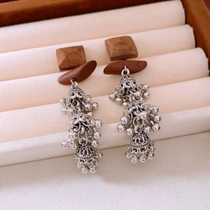 Close-up of ethnic style wooden square earrings with vintage silver tassel details