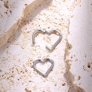 Detail of silver heart-shaped 316L stainless steel seamless hoop earrings on a stone base