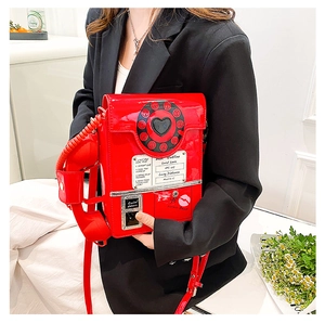 Detailed view of a red retro telephone crossbody bag with a coiled cord handle