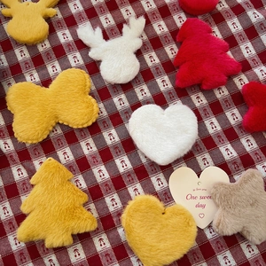 Flat lay of colorful plush Christmas ornaments like trees and stars on a plaid cloth