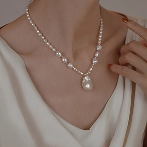 Close-up of Baroque pearl pendant necklace on model's neck with natural lighting
