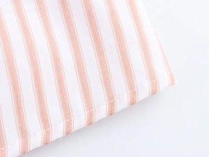 Detailed macro shot of pink and white striped fabric texture and neat stitching seams