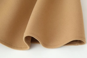 Detailed macro view of camel wool fabric texture and stitching on the coat hem