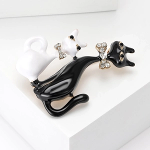 Close-up of black and white enamel cats brooch with rhinestone golden bows details