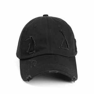 Detailed view of the distressed cotton fabric and ripped holes on this black baseball cap