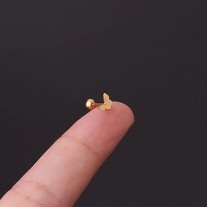 Macro shot of a tiny gold butterfly earring with screw back ball held on a fingertip