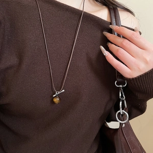 Detail view of retro tiger eye stone pendant with silver bar on long woven rope necklace