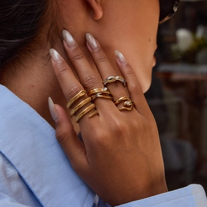 Detail of snake-shaped golden titanium steel rings with textured scales on model hand