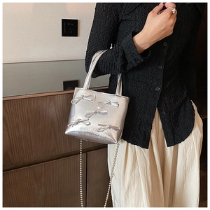 Close-up of a silver handbag with bow decorations and elegant bead chain strap detail