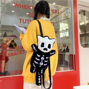 Bonito bolso de peluche gato monstruo negro con calavera llevado al hombro en un café