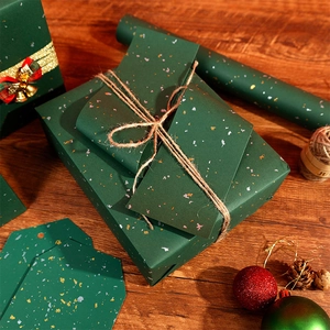 Dark green gift wrapping paper with gold speckles and festive holiday decorations