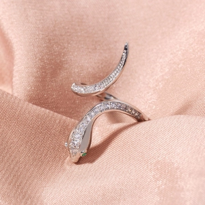 Detailed view of silver snake ring with sparkling white pavé stones and green gem eyes