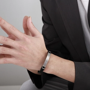 Nahaufnahme von Herren-Lederarmband mit silberner Metallplatte an einem männlichen Handgelenk