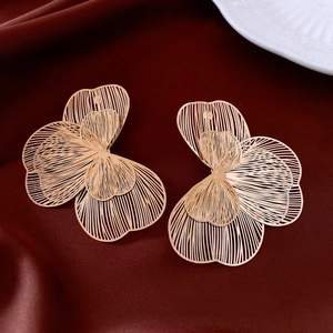 Detail of golden butterfly hollow earrings on red silk background, elegant jewelry art