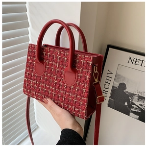 Detail of red tweed handbag with leather handle and golden hardware accessories