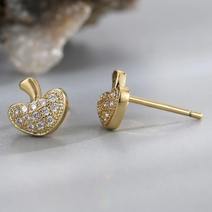 Macro detail of gold mushroom studs with white cubic zirconia on a stone surface