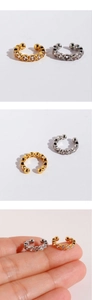 Close-up of gold and silver ear bone clips with zircon stones on a person's hand