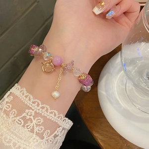 Detailed close-up of a purple amethyst beaded bracelet with a golden planet charm on a wrist