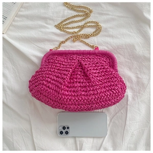 Top view of a magenta woven cloud bag with gold chain strap next to a smartphone