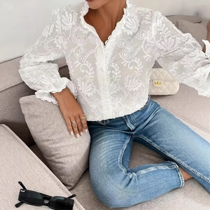 Détail de la broderie florale blanche et du col en V en dentelle de la chemise élégante