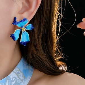 Close-up of vintage-style blue gradient enamel flower earrings worn by a model