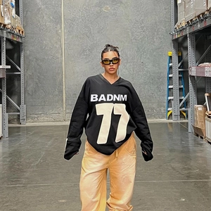Oversized black streetwear sweatshirt with BADNM 77 print and loose yellow trousers