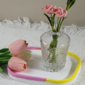 Macro shot of an oval resin jewelry tray with two pink roses on a white knit tablecloth