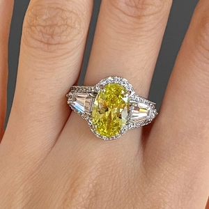 Detailopname van een luxe ovale gele edelsteen ring met trapezium diamanten op de hand